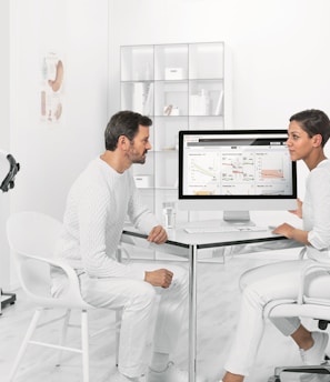 man in white dress shirt sitting on white chair in front of computer
