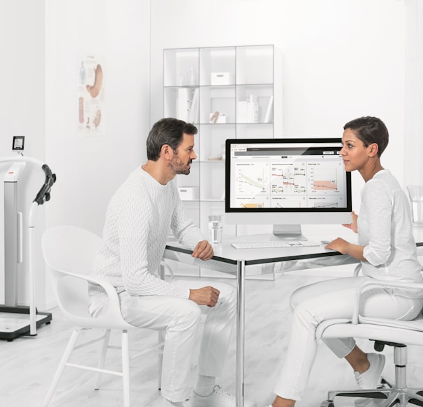 man in white dress shirt sitting on white chair in front of computer