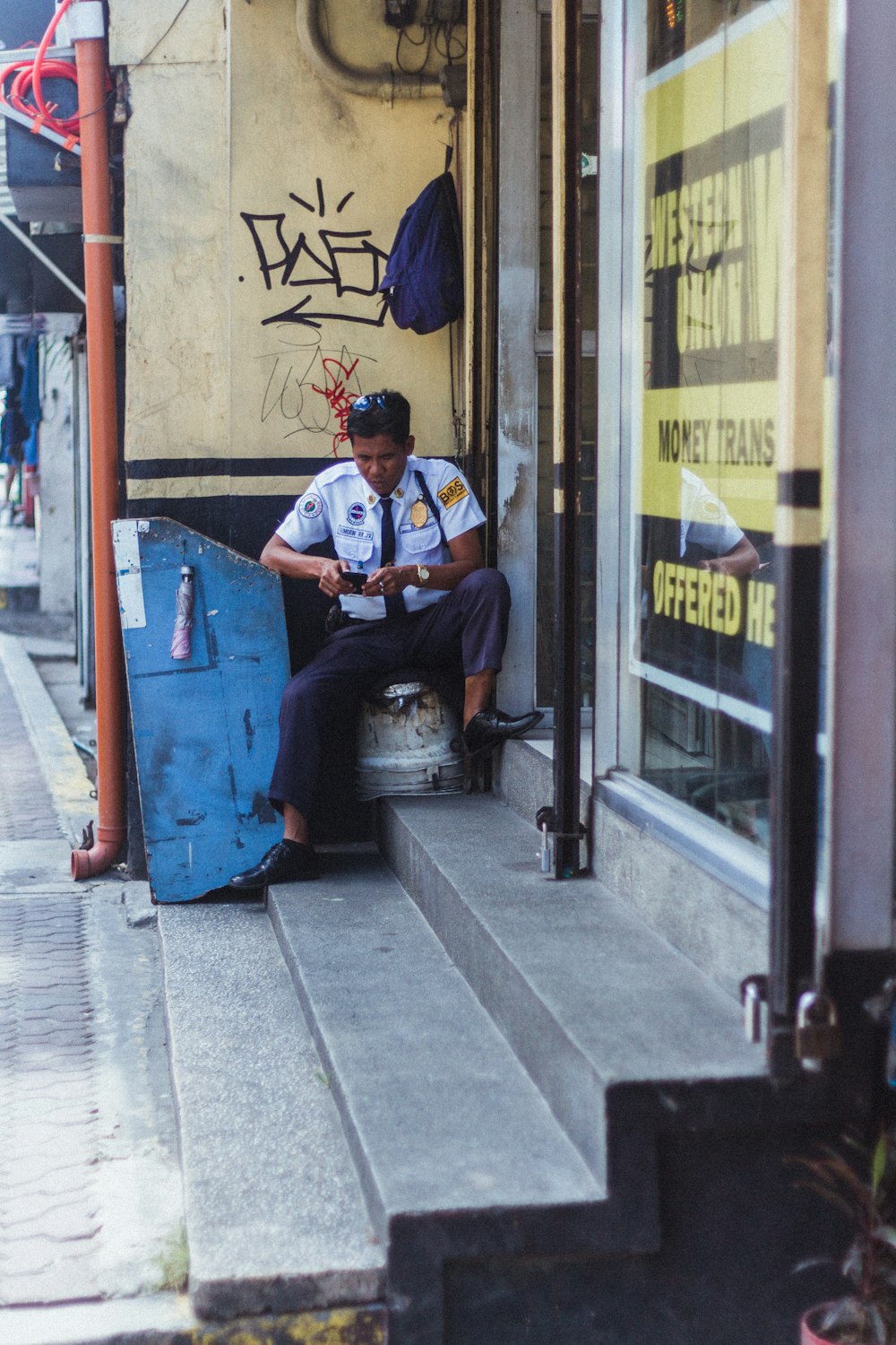 uomo in camicia a maniche lunghe blu e bianca seduto su una panca di legno blu