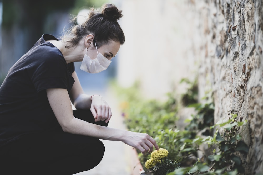 woman in black shirt holding yellow flower