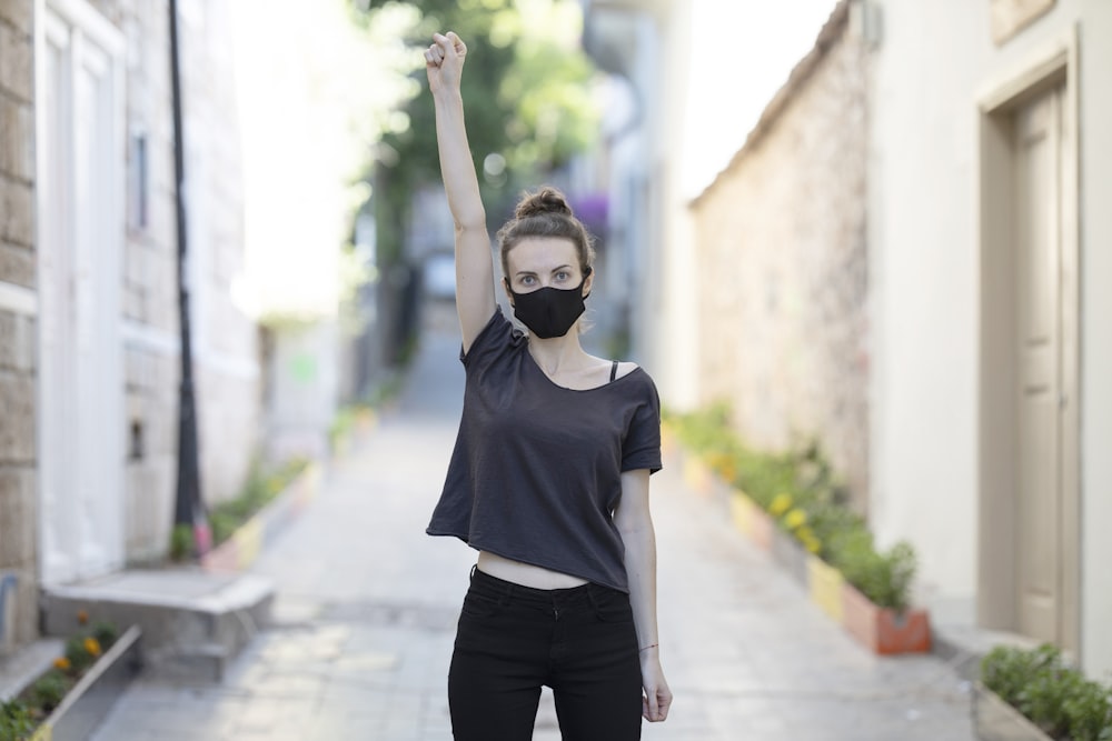 Femme en t-shirt à col rond noir et pantalon noir debout sur le trottoir pendant la journée