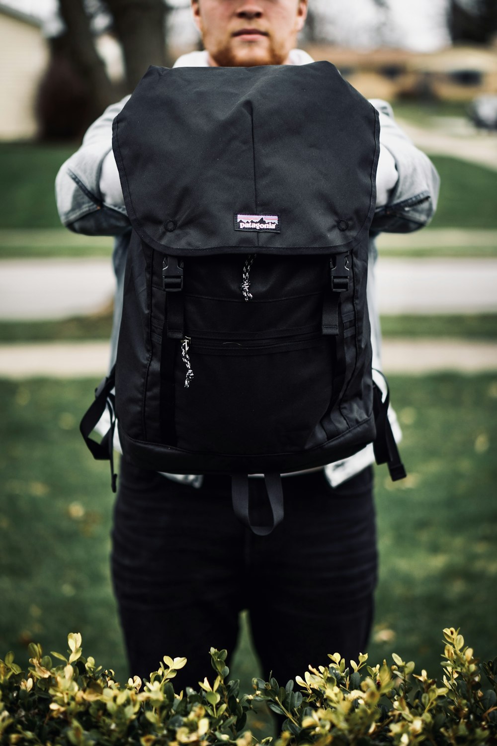 person in white shirt and black pants carrying black backpack