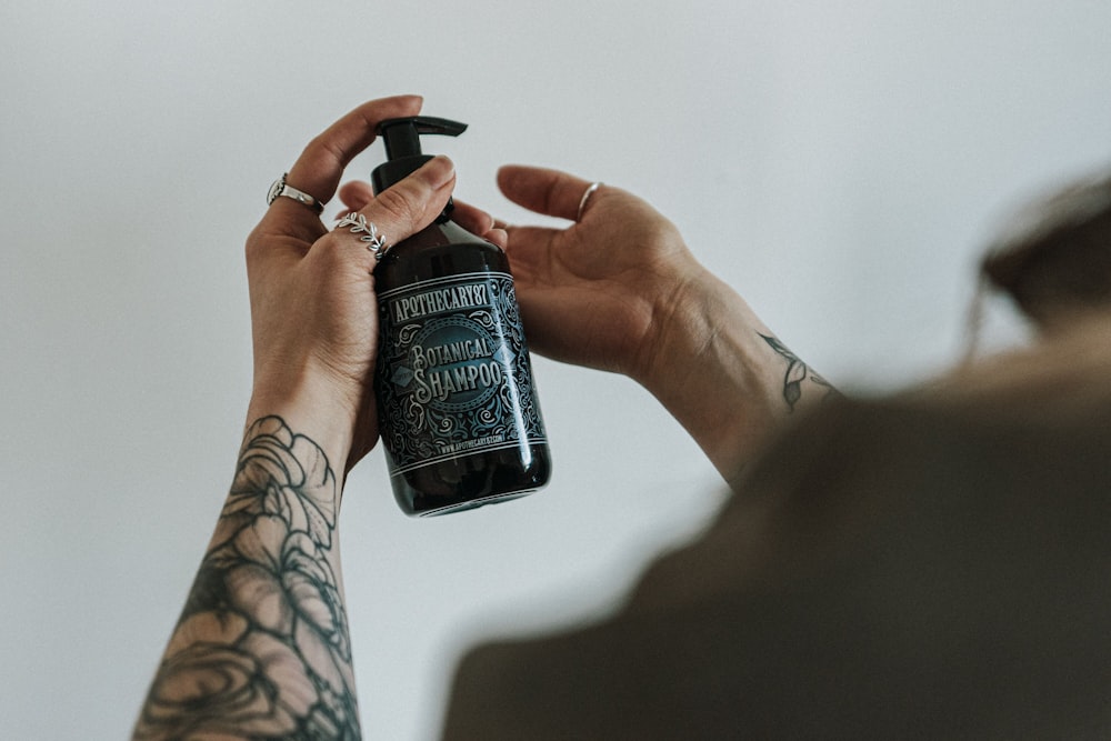 person holding black and white labeled bottle