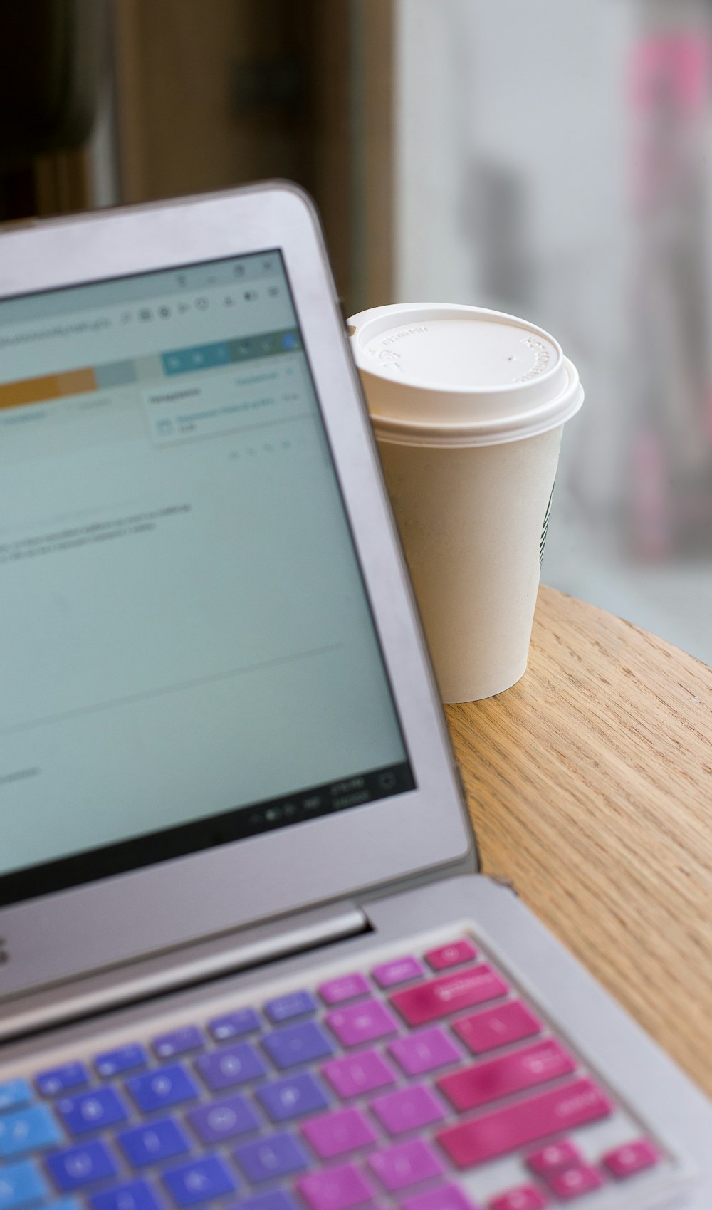 white disposable cup beside macbook air