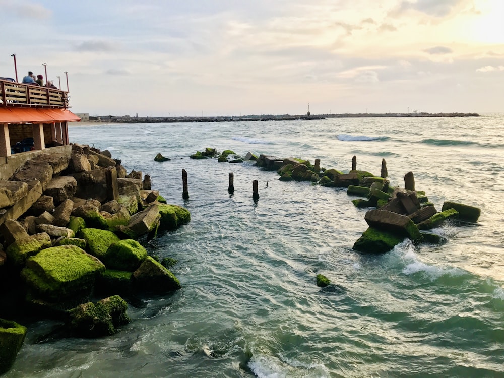 people on sea near red and white lighthouse under white clouds during daytime