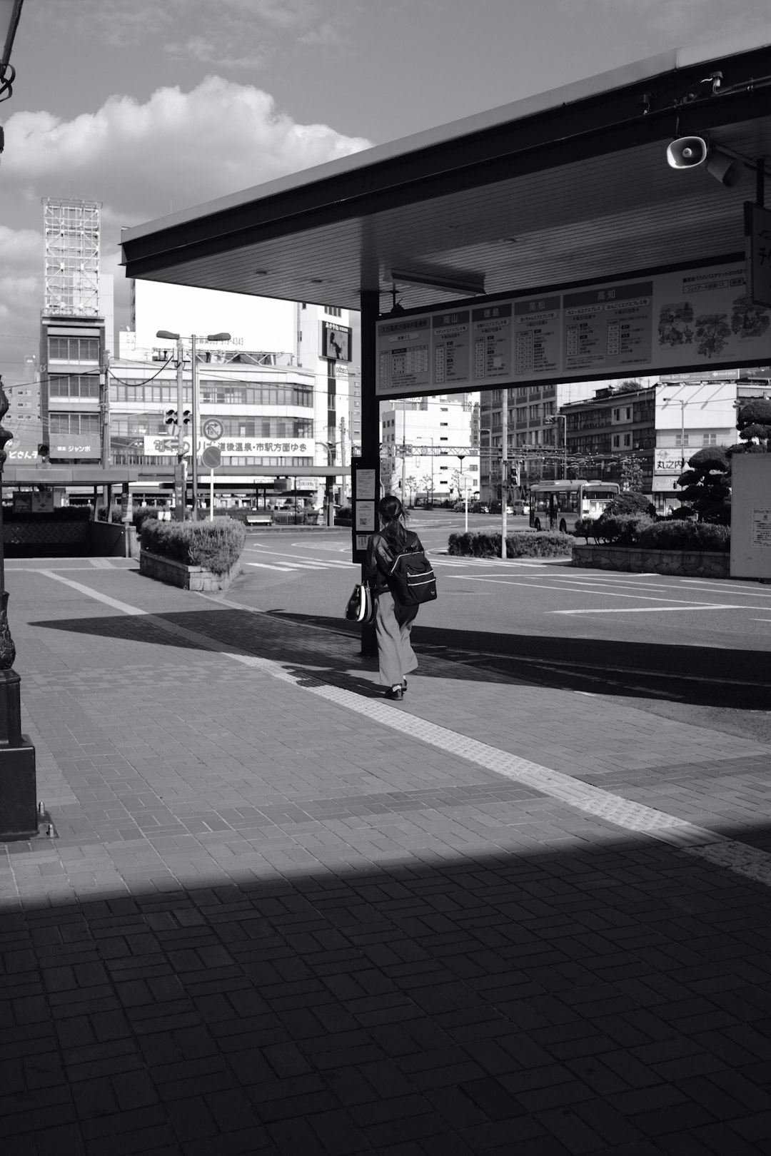 grayscale photo of woman walking on pedestrian lane