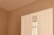 A section of a minimalist room featuring a white wardrobe against a light beige wall. The wardrobe includes a mirrored section that reflects part of a window with beige curtains. The clean lines and neutral tones create a calm, serene atmosphere.