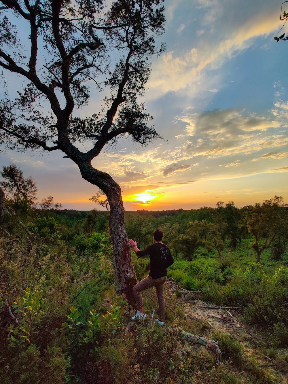 man in black t-shirt and brown shorts standing on green grass field during sunset