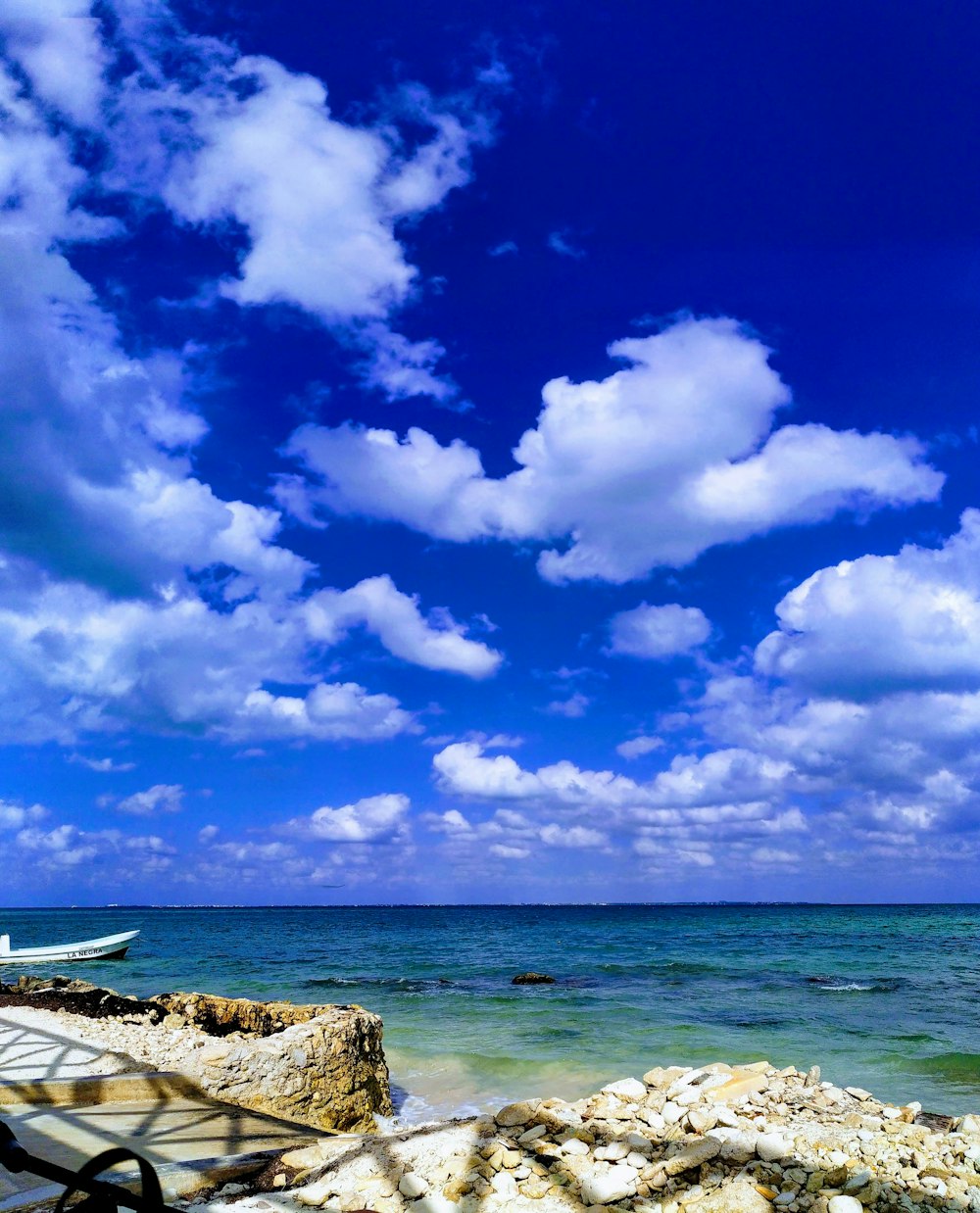 white boat on sea under blue sky and white clouds during daytime