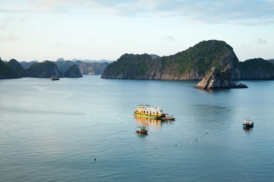 yellow boat on body of water near mountain during daytime in Ha Long Bay Vietnam