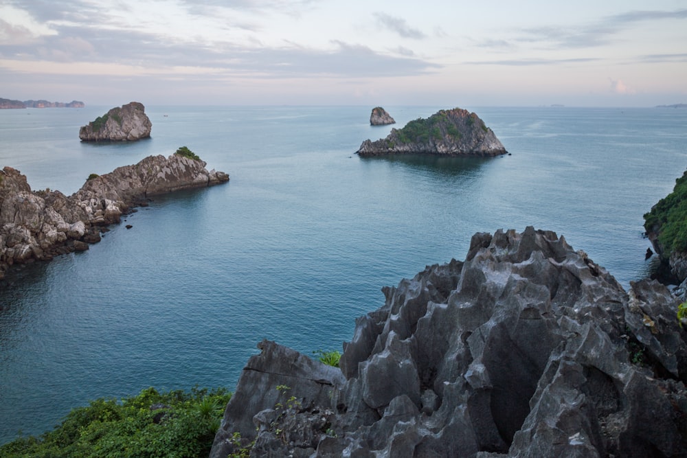 gray rocky mountain beside blue sea under blue sky during daytime