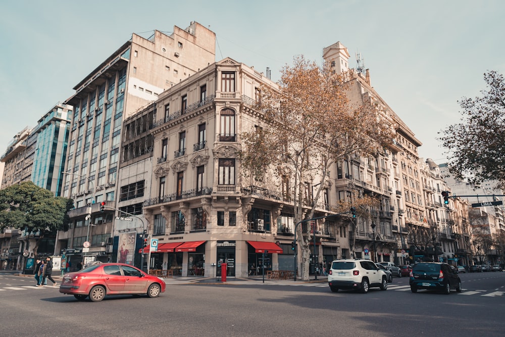 a red car driving down a street next to tall buildings