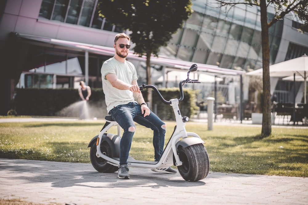 woman in white shirt and blue denim jeans riding white and black scooter during daytime