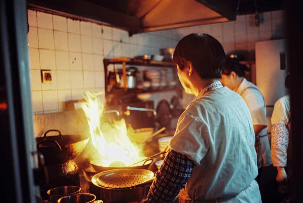 ストーブの上で料理をする白いシャツの男