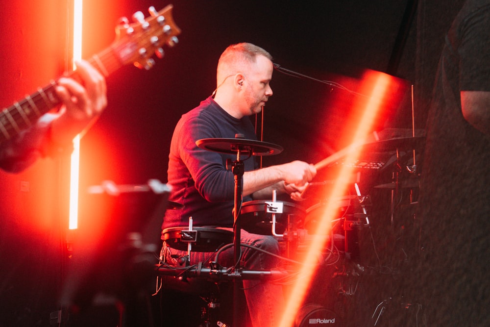 Mann im schwarzen Hemd spielt Schlagzeug