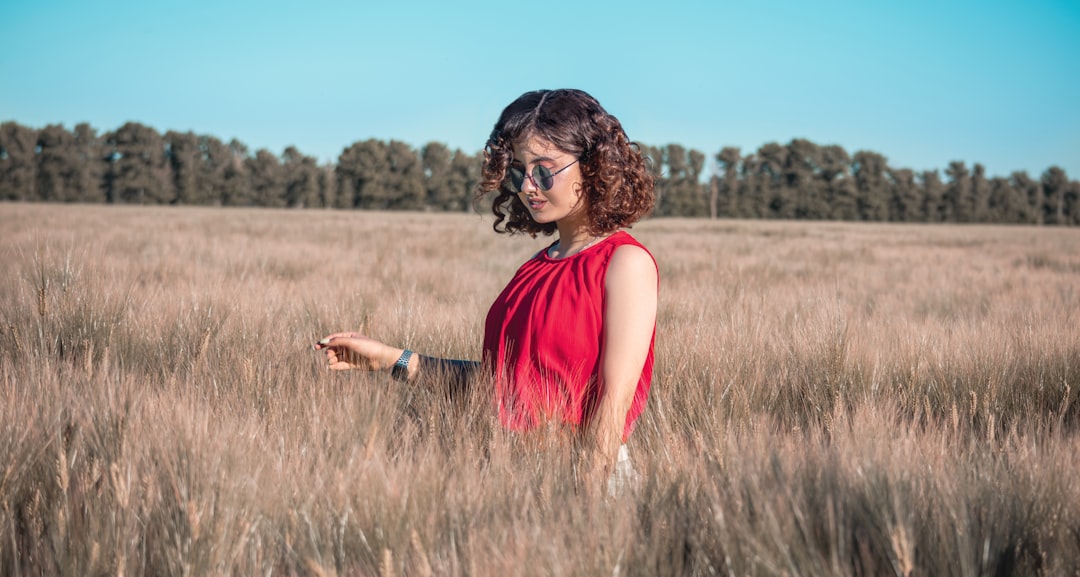 woman in red tank top standing on brown grass field during daytime