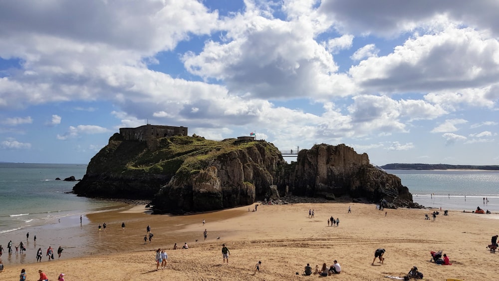 people on beach near mountain under white clouds and blue sky during daytime