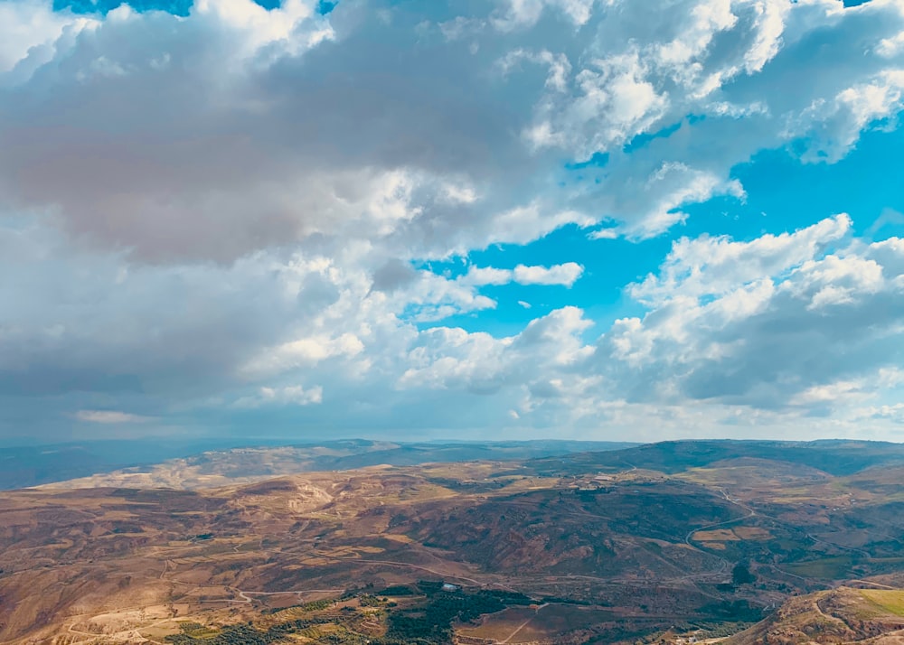 brown mountains under blue sky and white clouds during daytime