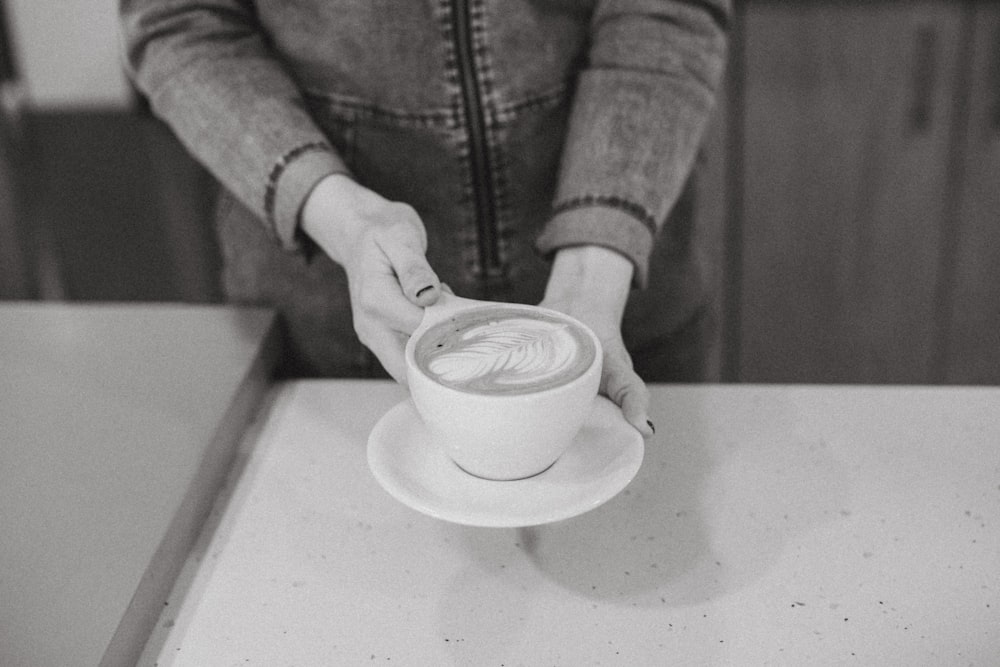 person pouring white ceramic cup on white ceramic saucer