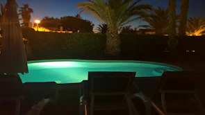 A newly finished backyard pool deck glowing softly under twilight with turquoise accents.