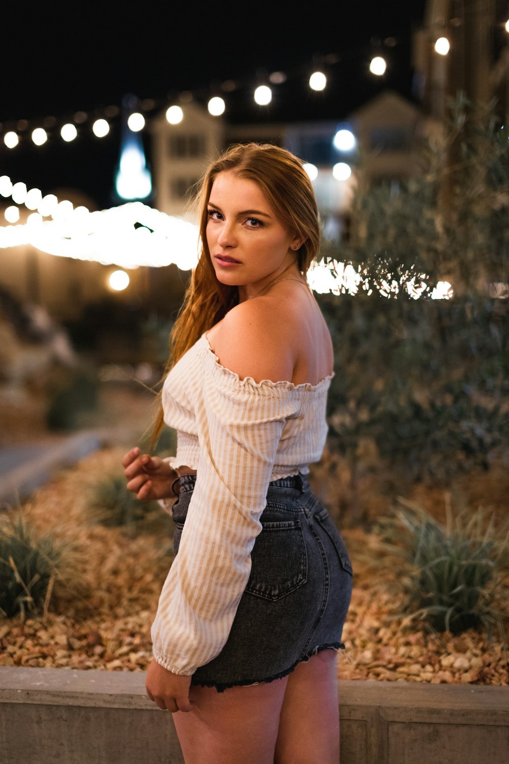 woman in white tank top and blue denim jeans standing on green grass field during daytime