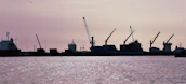 Panoramic view of Mazatlán's industrial harbor at dawn with ships and cranes silhouetted against the sky.