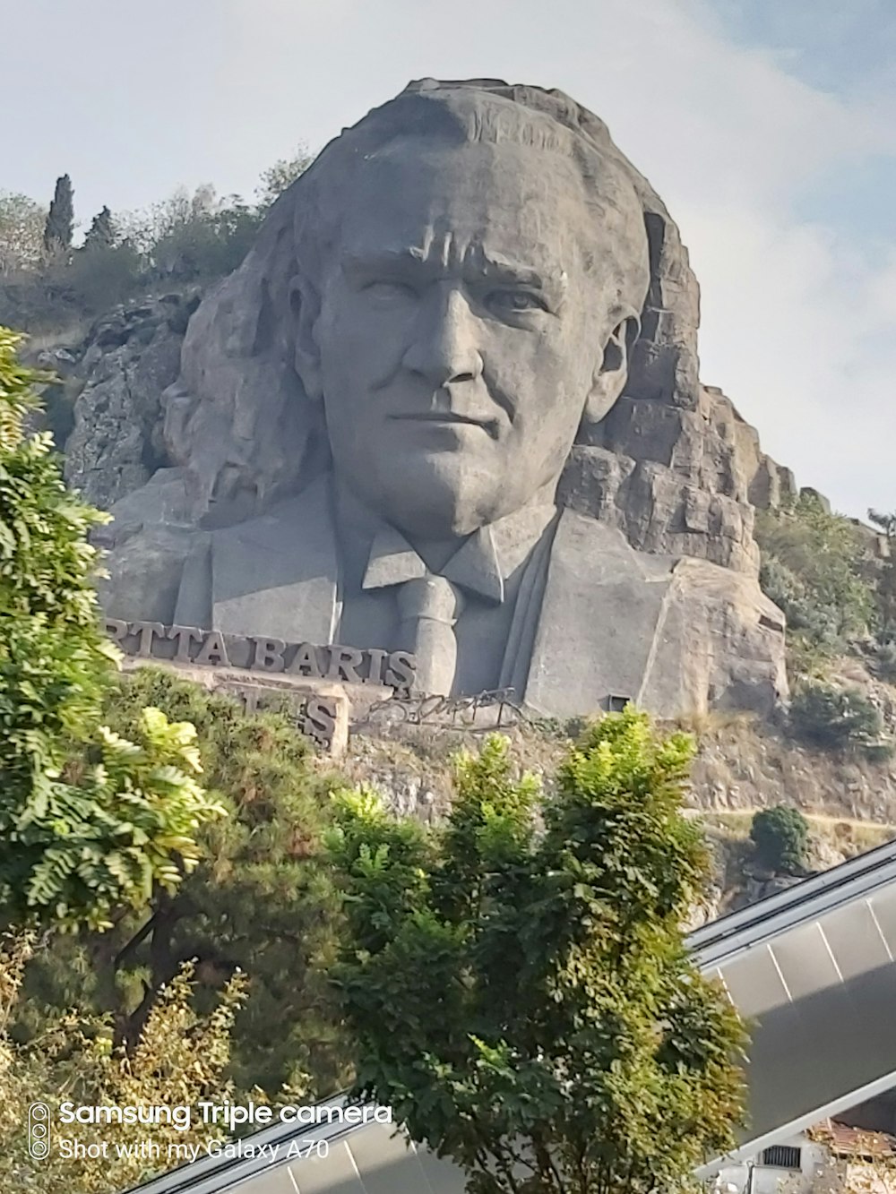 statue en béton gris près des arbres verts pendant la journée