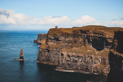 white lighthouse on brown rock formation near body of water during daytime