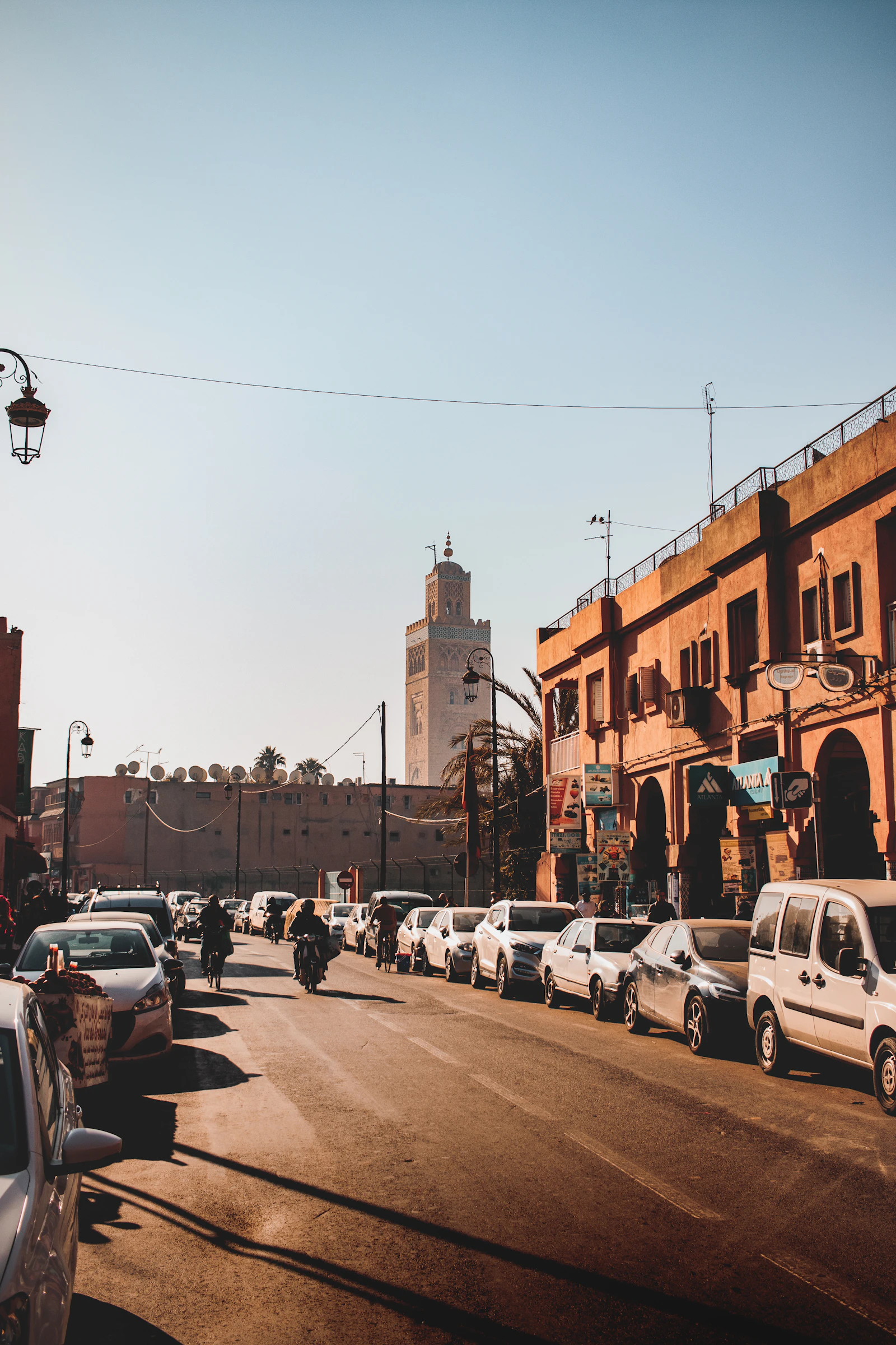 Parked cars beside ochre buildings and a mosque in Marrakech