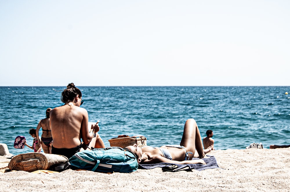 man and woman lying on beach sand during daytime