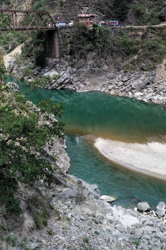 green river between gray rocky mountain during daytime in Uttarakhand India