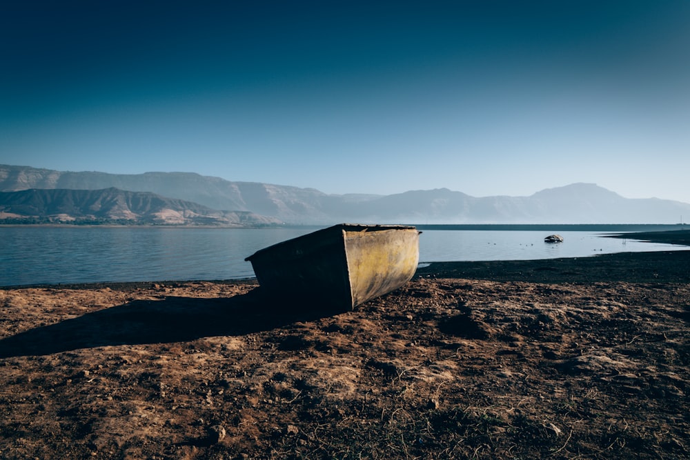 brown wooden boat on brown sand near body of water during daytime