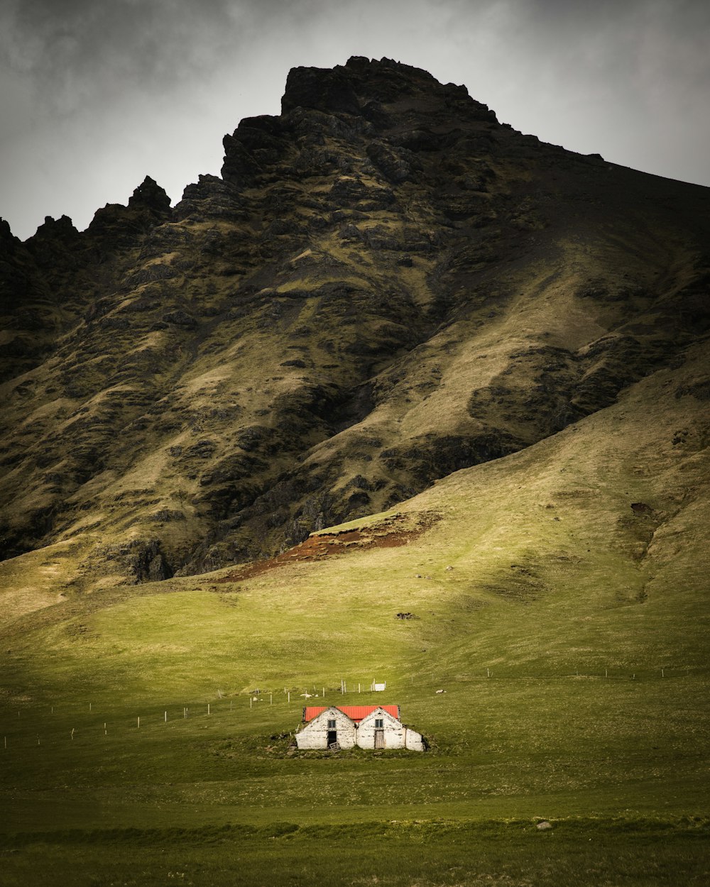 white and red house on green grass field near mountain