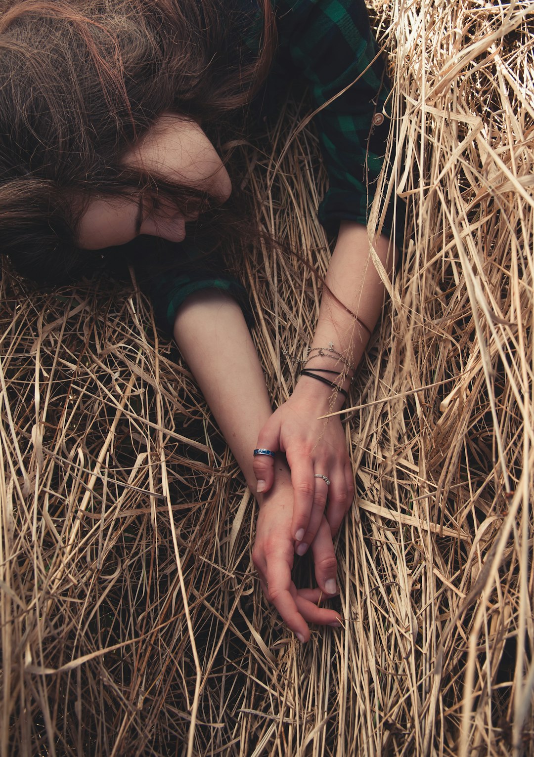 woman in green shirt lying on brown dried grass