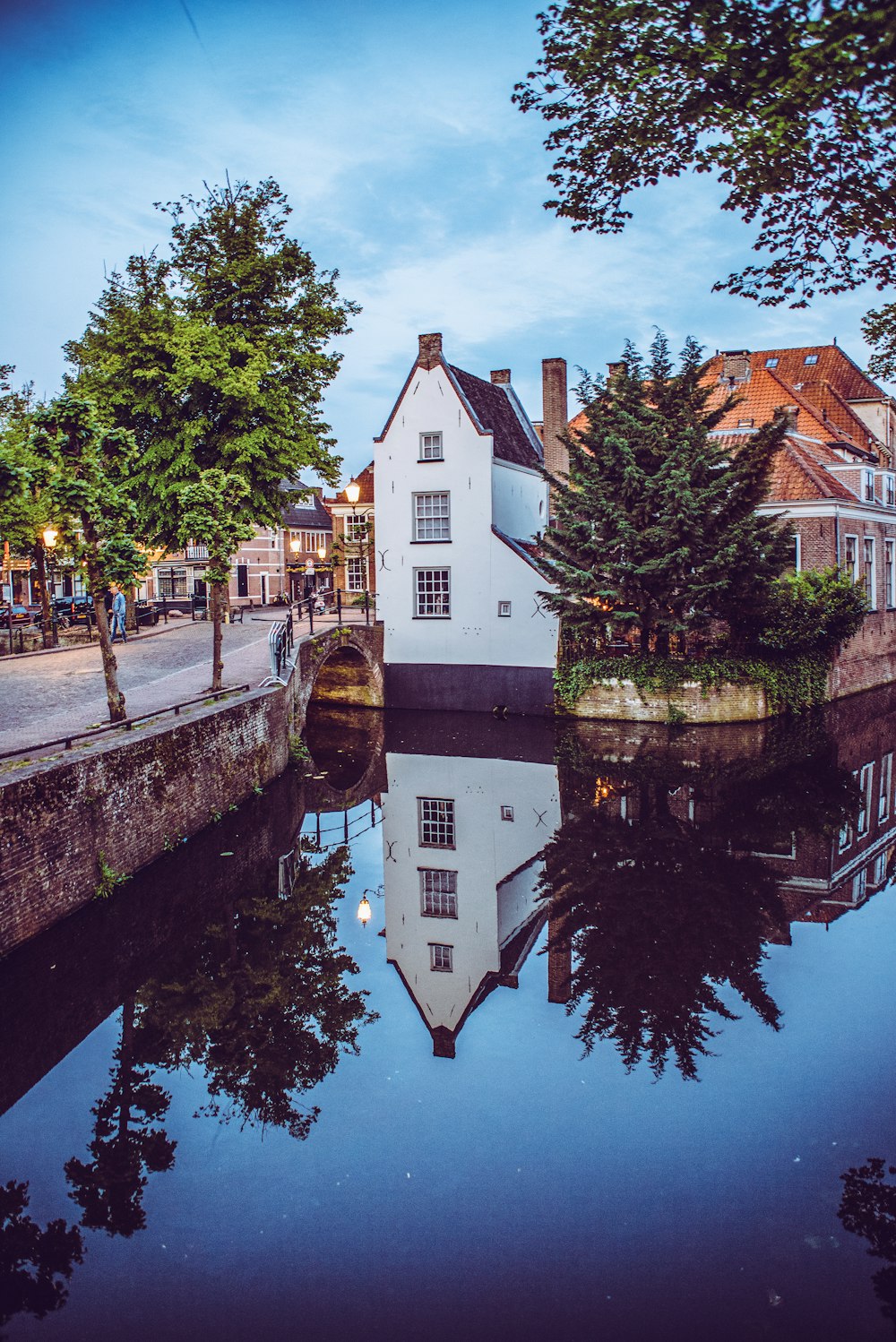 Edificio de hormigón blanco y marrón junto a árboles verdes y río durante el día