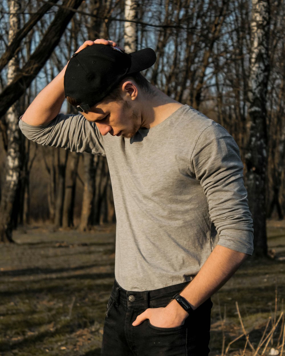 man in gray crew neck t-shirt and black denim jeans standing on brown grass field