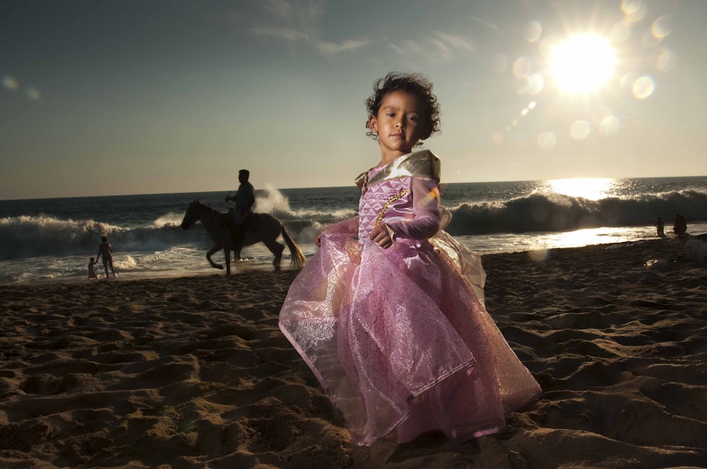 낮 동안 해변에 서 있는 보라색 드레스를 입은 여자