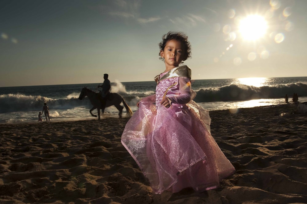 Mujer en vestido púrpura de pie en la playa durante el día