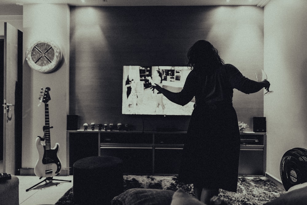 woman in black long sleeve dress standing in front of black flat screen tv
