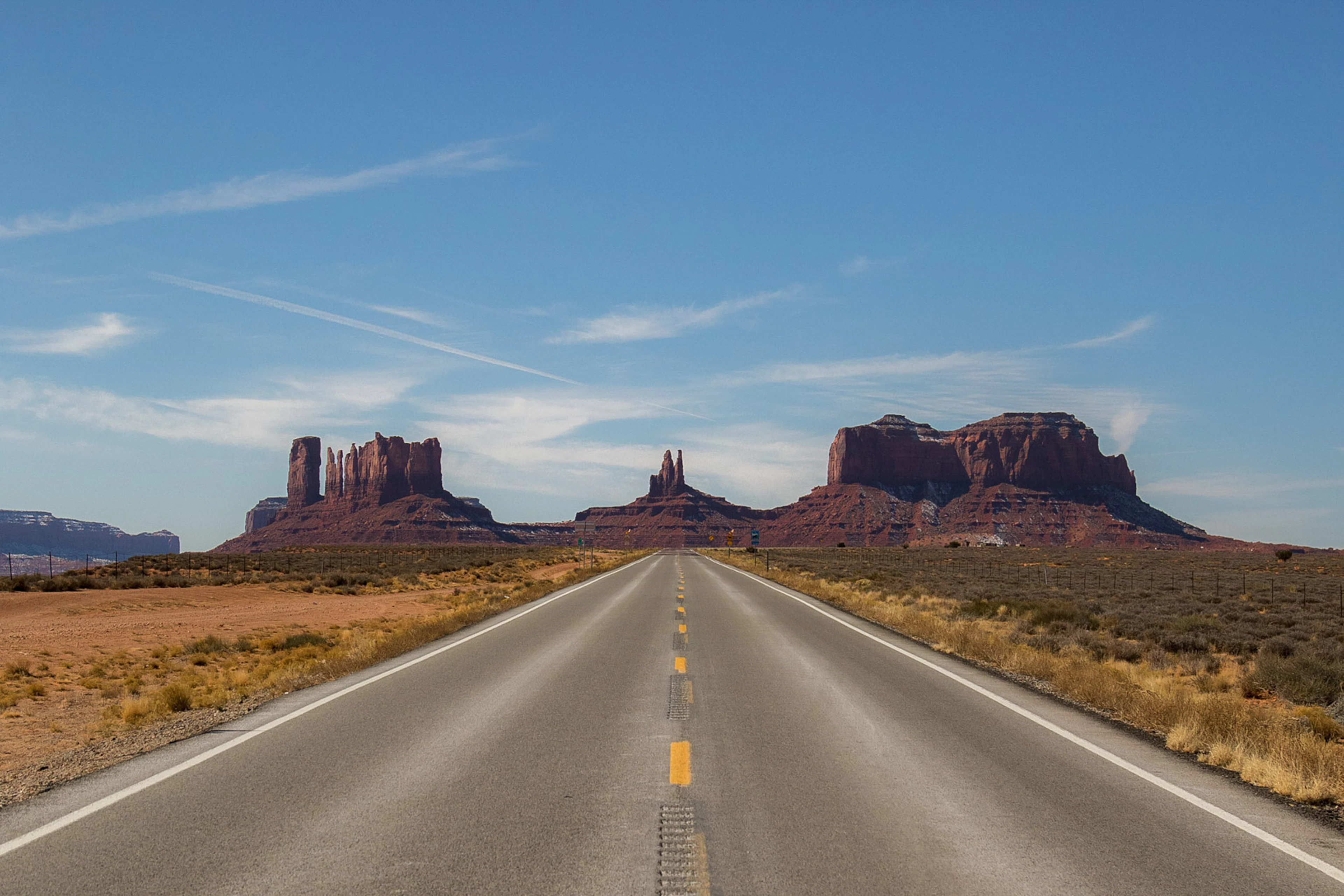 A straight road leading towards the red buttes of Monument Valley