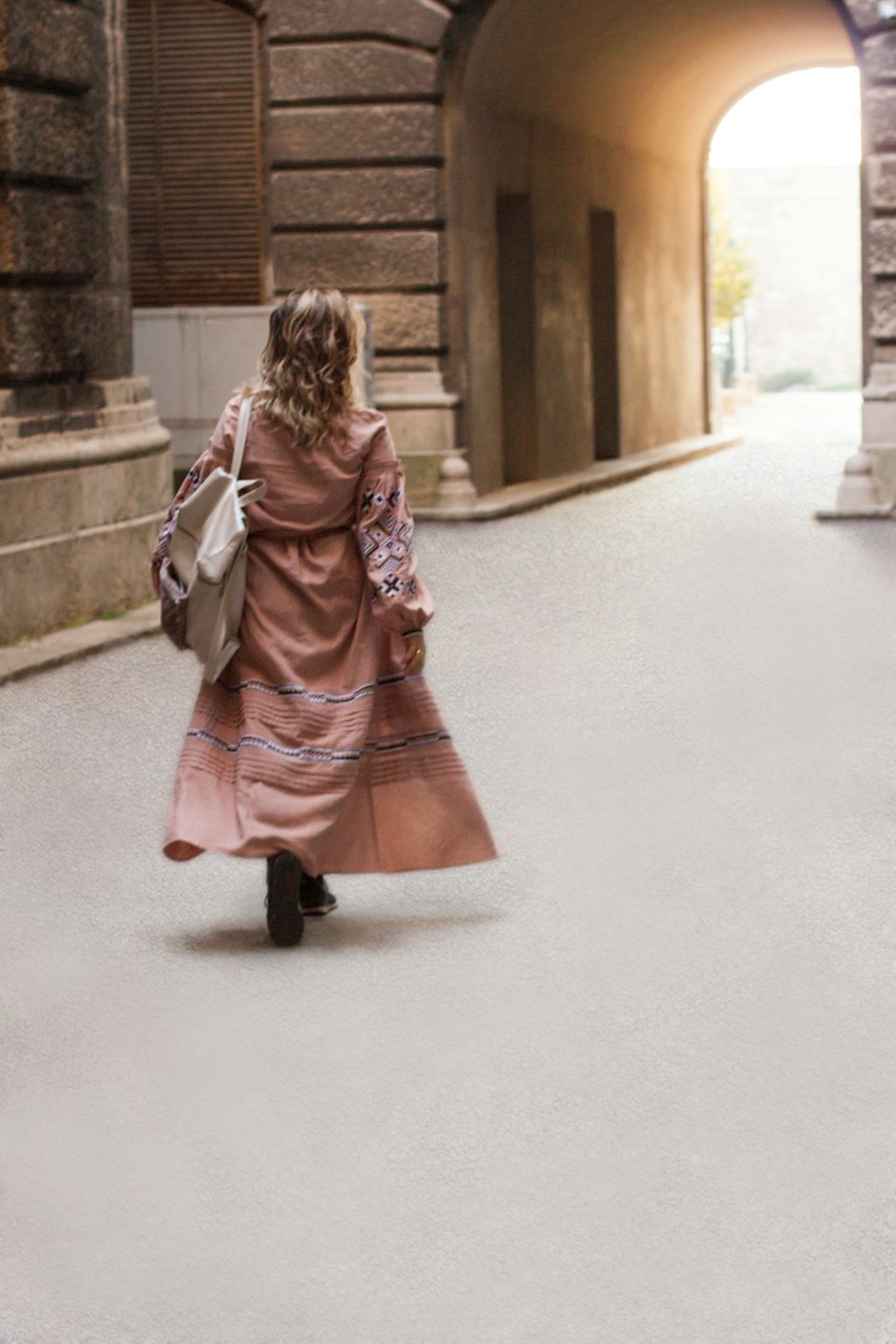 woman in red and brown dress walking on gray concrete floor during daytime