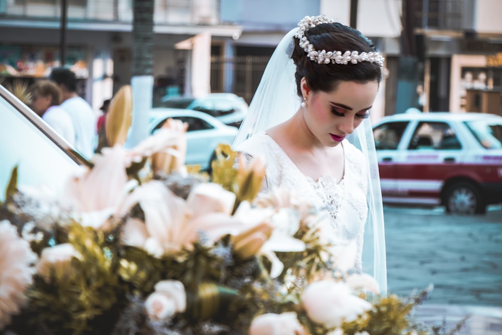 mujer en vestido de novia blanco sosteniendo ramo de flores