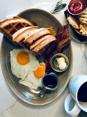 A vibrant breakfast plate with eggs, crispy bacon, and waffles