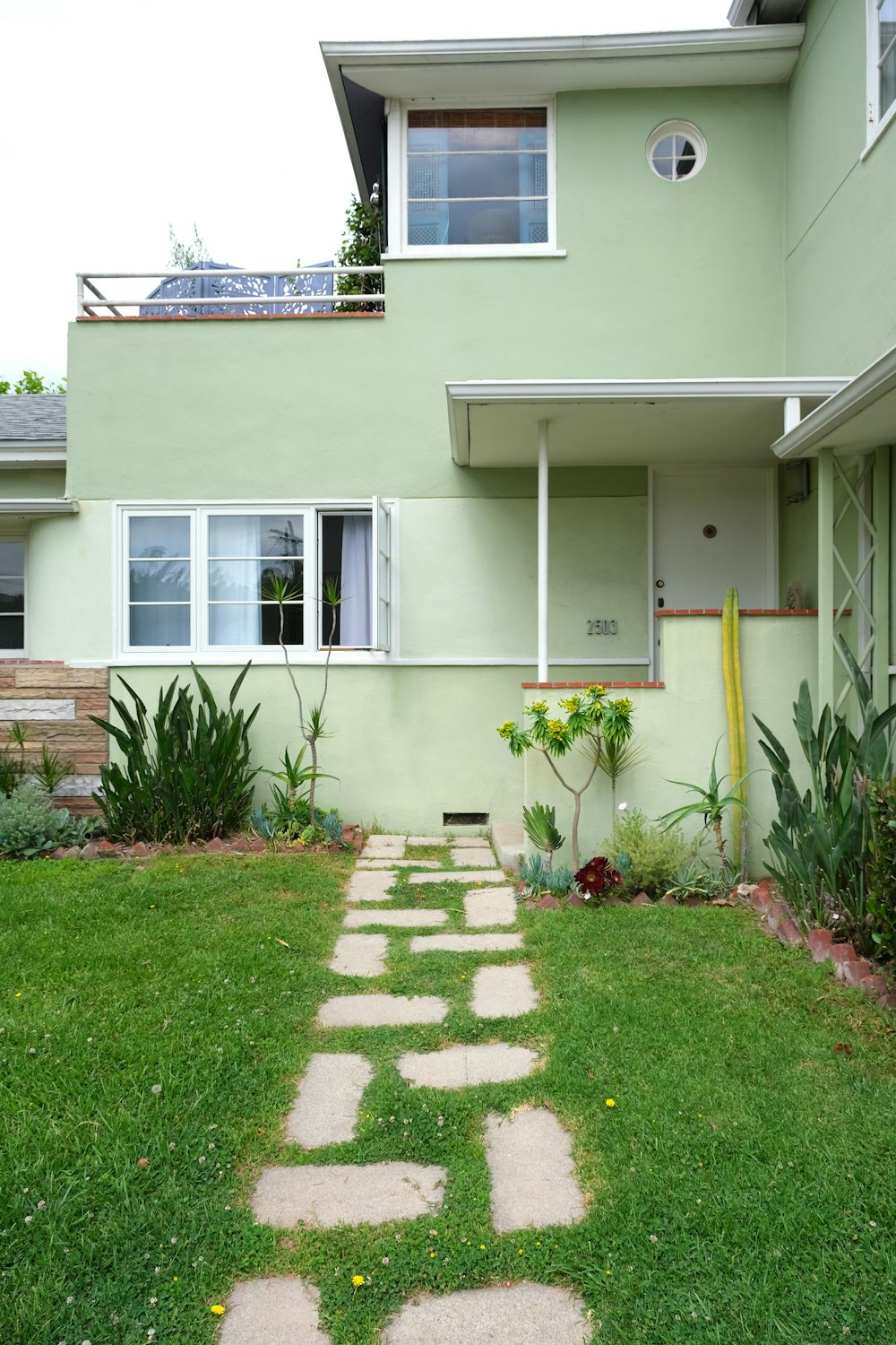 green grass lawn in front of white concrete house