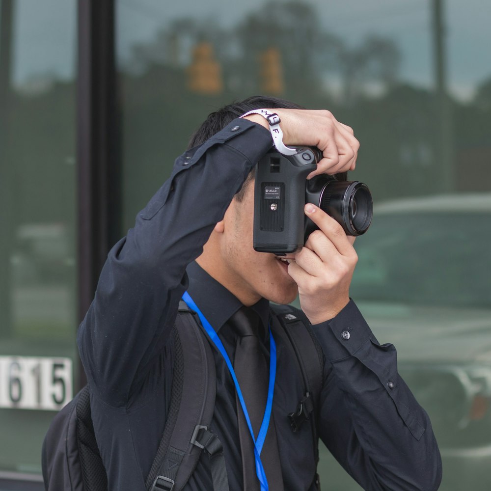 man in black jacket holding black dslr camera