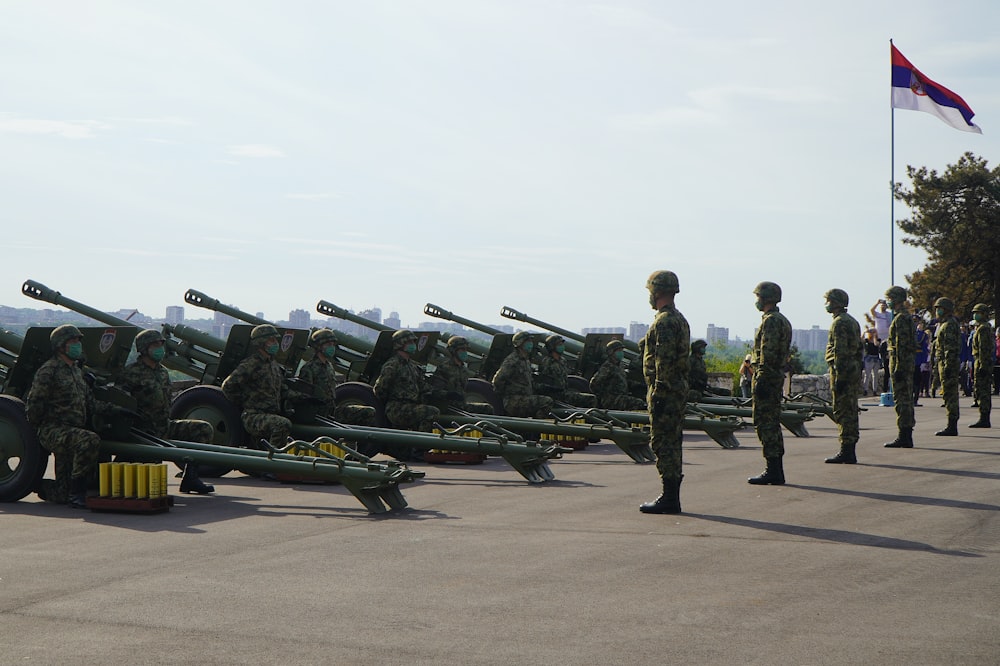 soldiers in green camouflage uniform standing on gray asphalt road during daytime