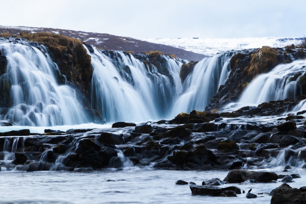 water falls on rocky shore during daytime