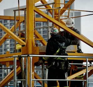 man in black jacket and helmet climbing orange ladder