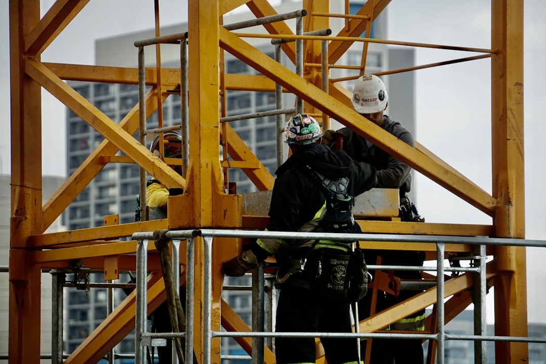 man in black jacket and helmet climbing orange ladder,