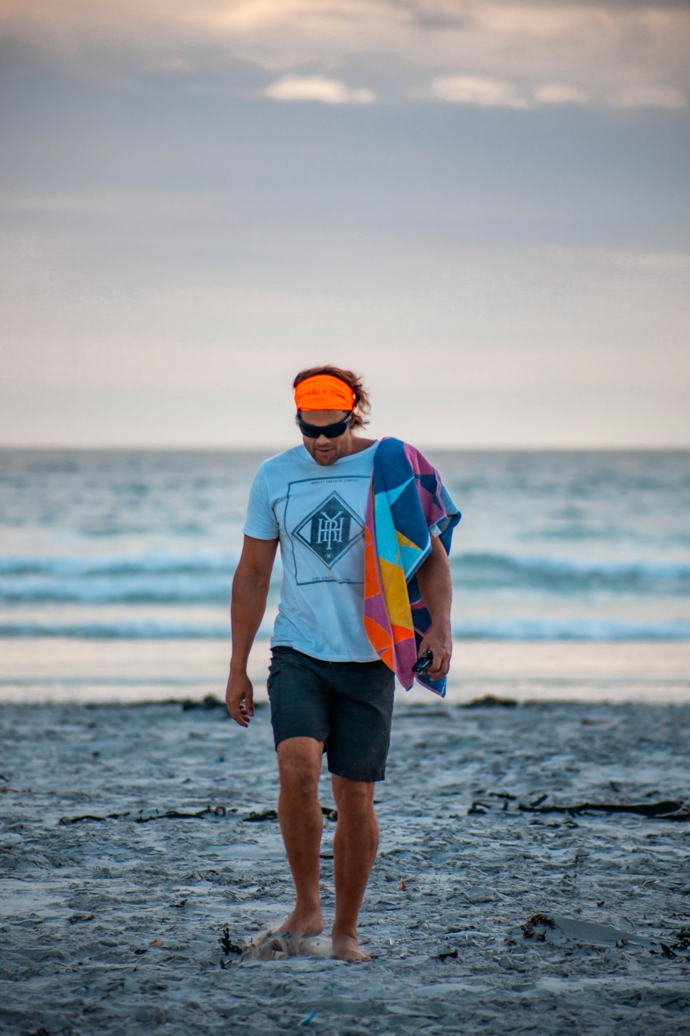 man in white and orange crew neck t-shirt and green shorts standing on beach during